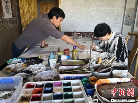 圖為2020年8月下旬，敦煌“80后”畫家張杰龍(左)在為云南麗江“學(xué)生”莫北講解敦煌壁畫的繪畫技巧。　馮志軍 攝