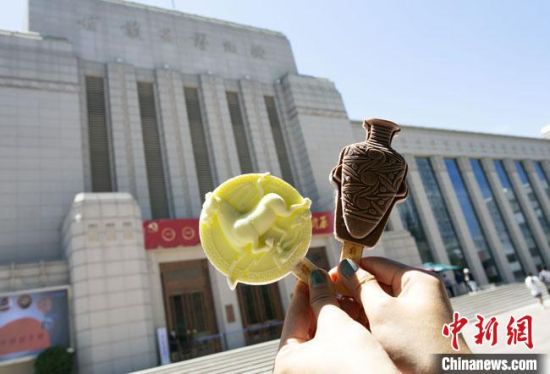 2021年7月30日，游客手拿“銅奔馬”“彩陶瓶”造型的雪糕，在甘肅省博物館前拍照打卡。　高展 攝