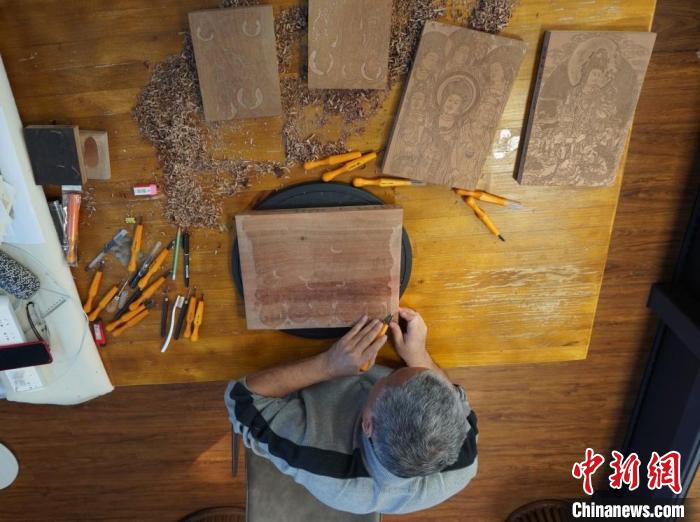 圖為徐晉林正在梨木木板上雕刻敦煌壁畫(huà)?！【琶赖┰?　攝