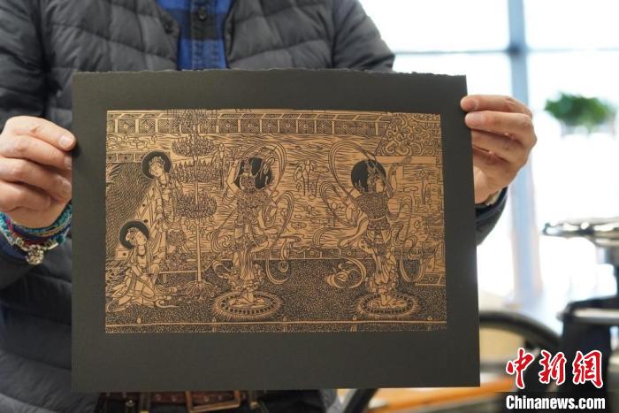 圖為手工書(shū)藝人展示敦煌雕版壁畫(huà)印刷品。　九美旦增 　攝