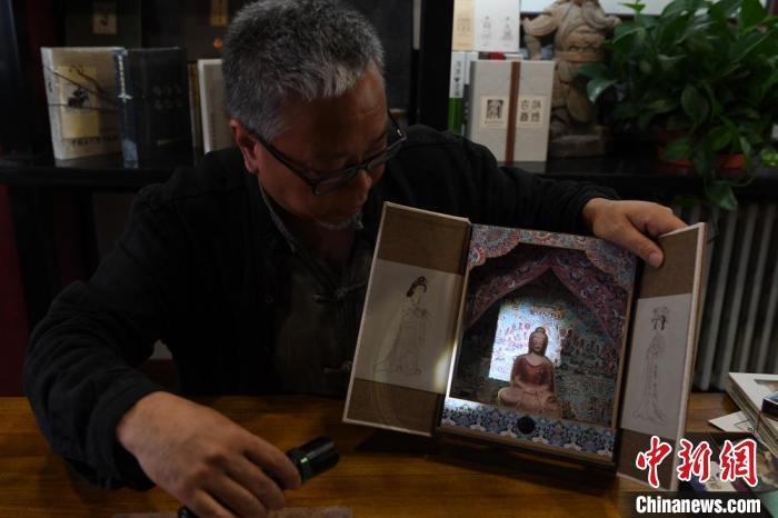 圖為讀者出版集團(tuán)讀者晉林工作室獨(dú)立出品人徐晉林，展示互動(dòng)性強(qiáng)的敦煌題材手工書。(資料圖) 楊艷敏 攝