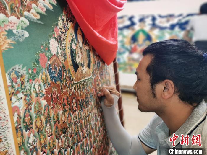 圖為更登才讓的徒弟繪畫唐卡?！?zhí)砀?攝