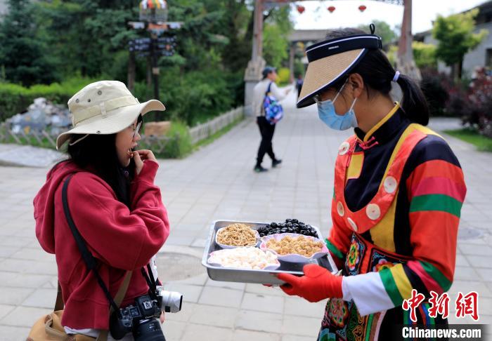 圖為身穿土族服飾的女性介紹當(dāng)?shù)靥厣〕??！⊙Φ?攝