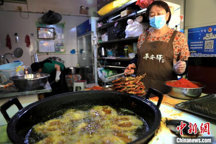 圖為平安驛·河湟民俗文化體驗(yàn)地內(nèi)的商戶炸干板魚?！⊙Φ?攝