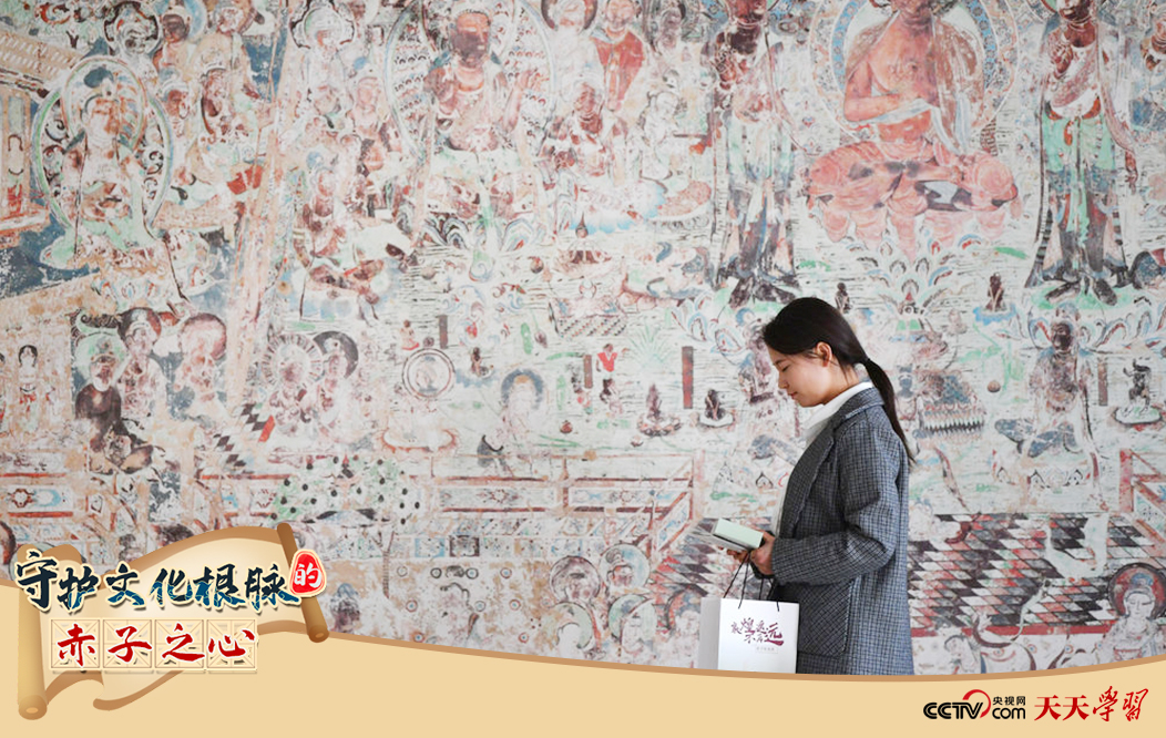 2023年4月25日，敦煌研究院文物數(shù)字化保護團隊創(chuàng)意營銷人員廖雪婷從一幅高保真復(fù)制壁畫前走過。