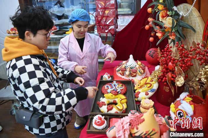 1月25日，隨著春節(jié)臨近，蘭州一花饃店“龍”元素花饃熱銷(xiāo)。圖為工作人員向顧客推薦“龍”元素花饃。九美旦增 攝</p><p>