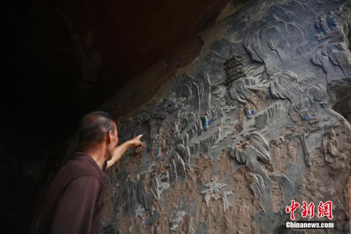 7月15日，甘肅省平?jīng)鍪袥艽h百里石窟長廊羅漢洞石窟內(nèi)，該窟文保員郭建平介紹窟內(nèi)石刻彩繪壁畫。郭建平家中三代人曾自發(fā)保護羅漢洞石窟。羅漢洞石窟遺存40余個窟龕，以北魏至清代風格為主。中新社記者 李亞龍 攝