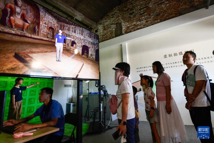 7月22日，游客體驗(yàn)“尋境敦煌——數(shù)字敦煌沉浸展”后，在虛擬演播廳拍攝一段真人與洞窟虛擬場(chǎng)景交互的視頻。新華社記者 郎兵兵 攝</p>
<p>