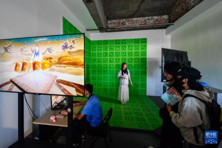 7月22日，游客體驗(yàn)“尋境敦煌——數(shù)字敦煌沉浸展”后，在虛擬演播廳拍攝一段真人與洞窟虛擬場(chǎng)景交互的視頻。新華社記者 郎兵兵 攝</p>
<p>